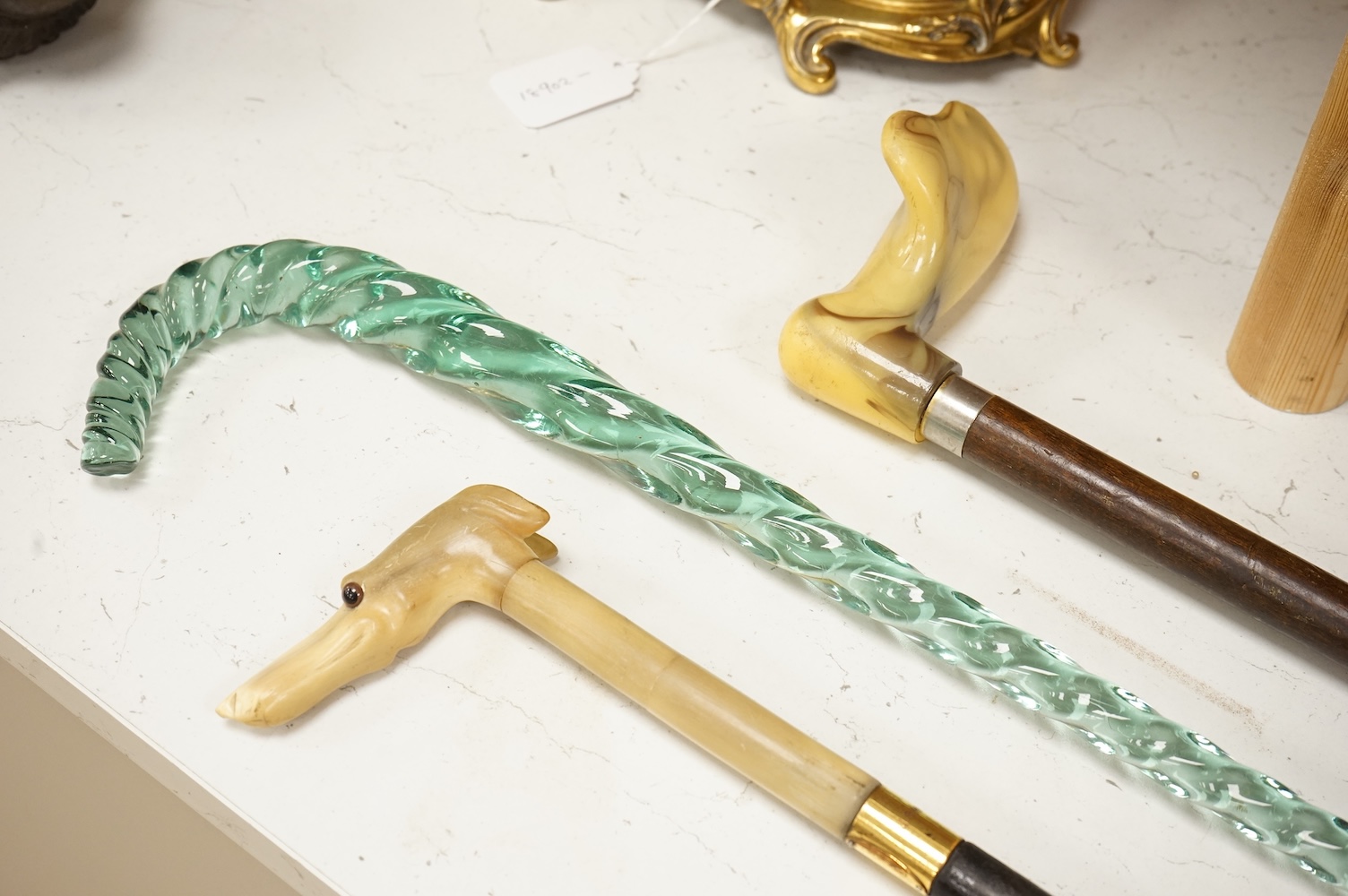 Four walking sticks to include a Brigg of London with carved horn handle in the form of a dogs head and a barley twist glass example, largest 123cm in length